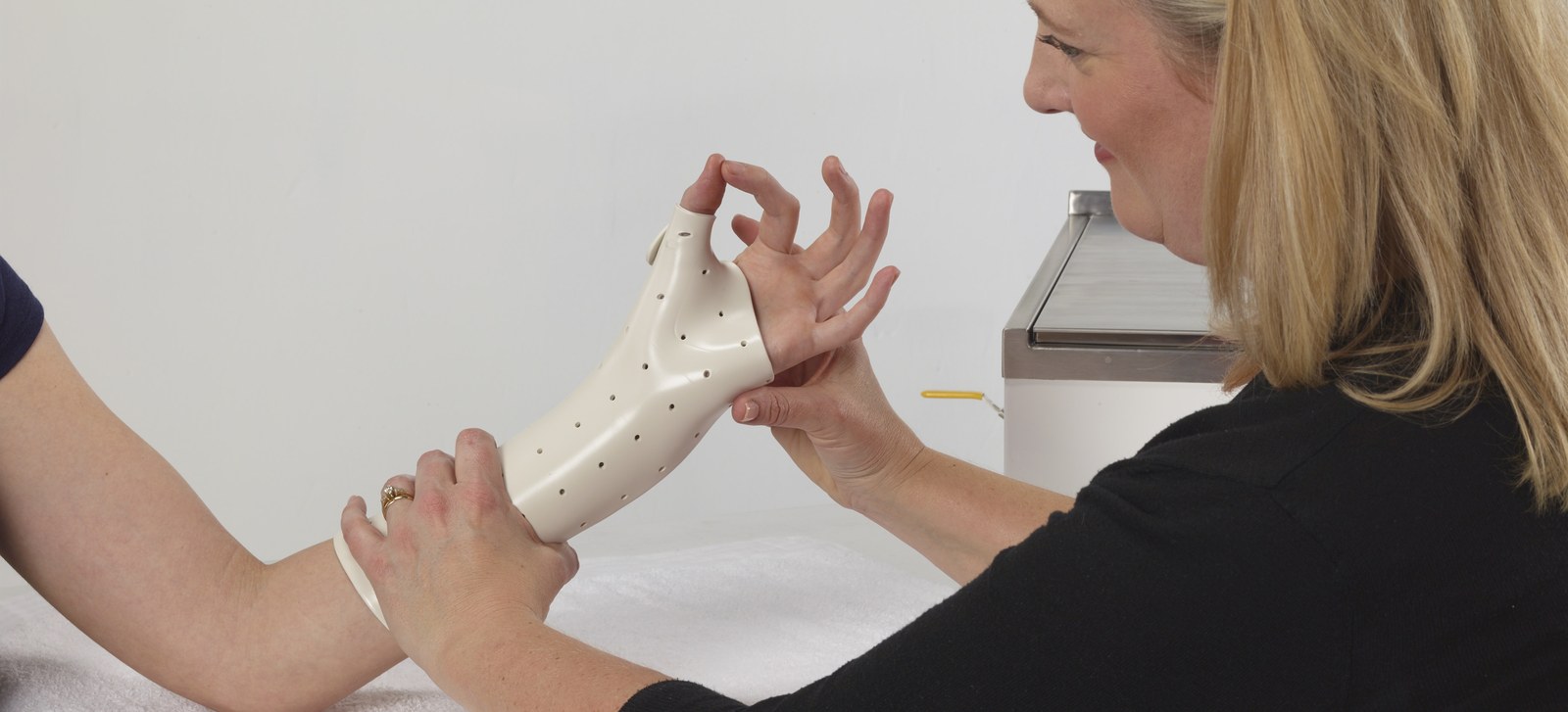Eine Therapeutin formt eine thermoplastische Schiene am Handgelenk einer Patientin